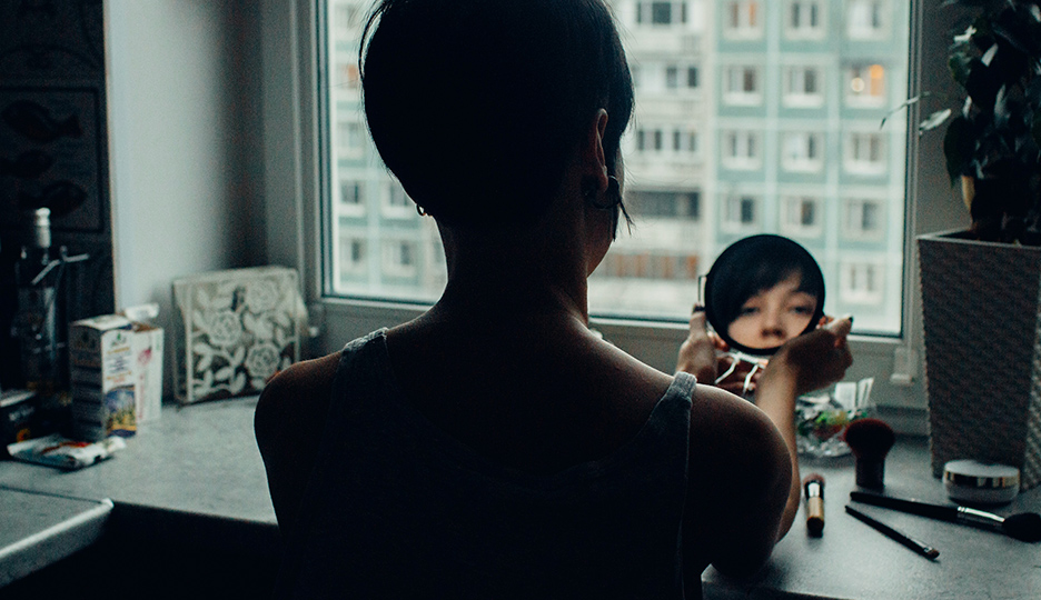 A imagem mostra a uma mulher de costas olhando parao espelho. A foto representa o post de baixa autoestima do Inbracer.
